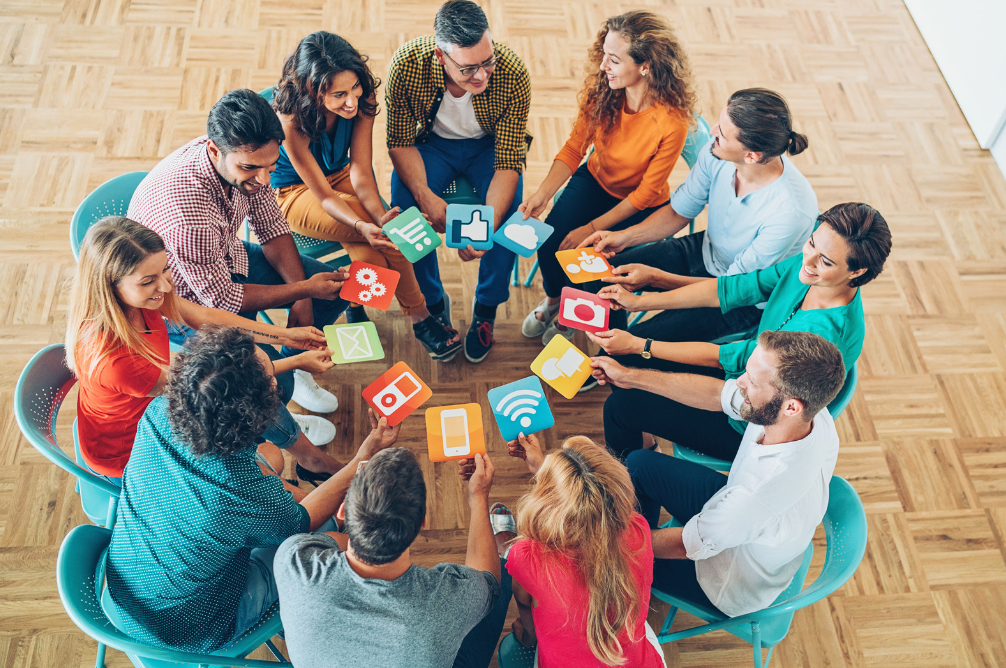 Group of people seated in a circle holding social media icon signs